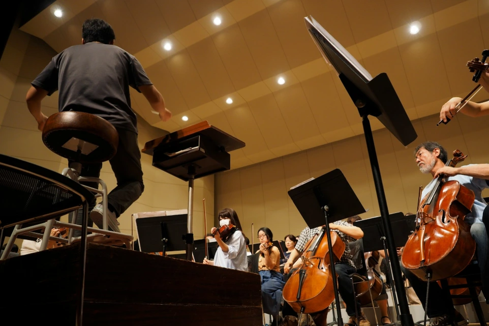 An orchestra rehearses with a conductor.